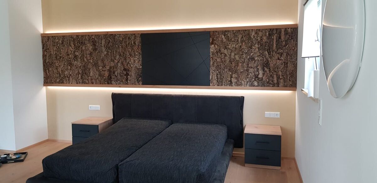 Schlafzimmer mit beleuchteter Wandnische über dem Bett und passenden Nachttischen