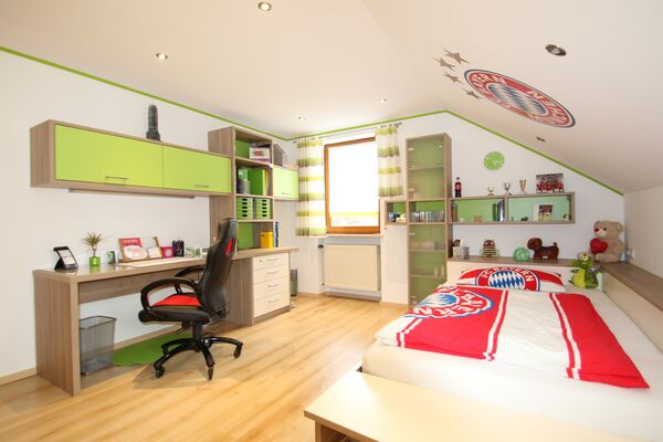 Jugendzimmer mit grünen Regalfronten, Schreibtisch und Bett unter der Dachschräge