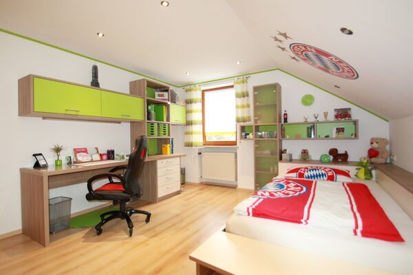 Jugendzimmer mit Schreibtisch, grünen Fronten und Bett unter der Dachschräge