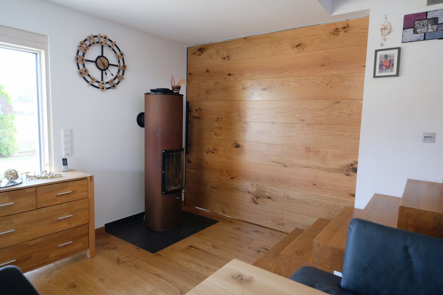 Wohnraum mit großflächiger Wandverkleidung aus Eiche neben Kaminofen und Sideboard