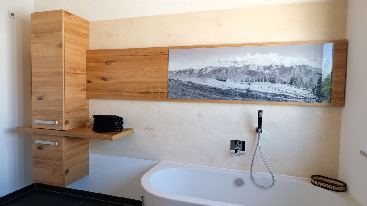 Badewanne mit Holzverkleidung und Ablage an der Wand