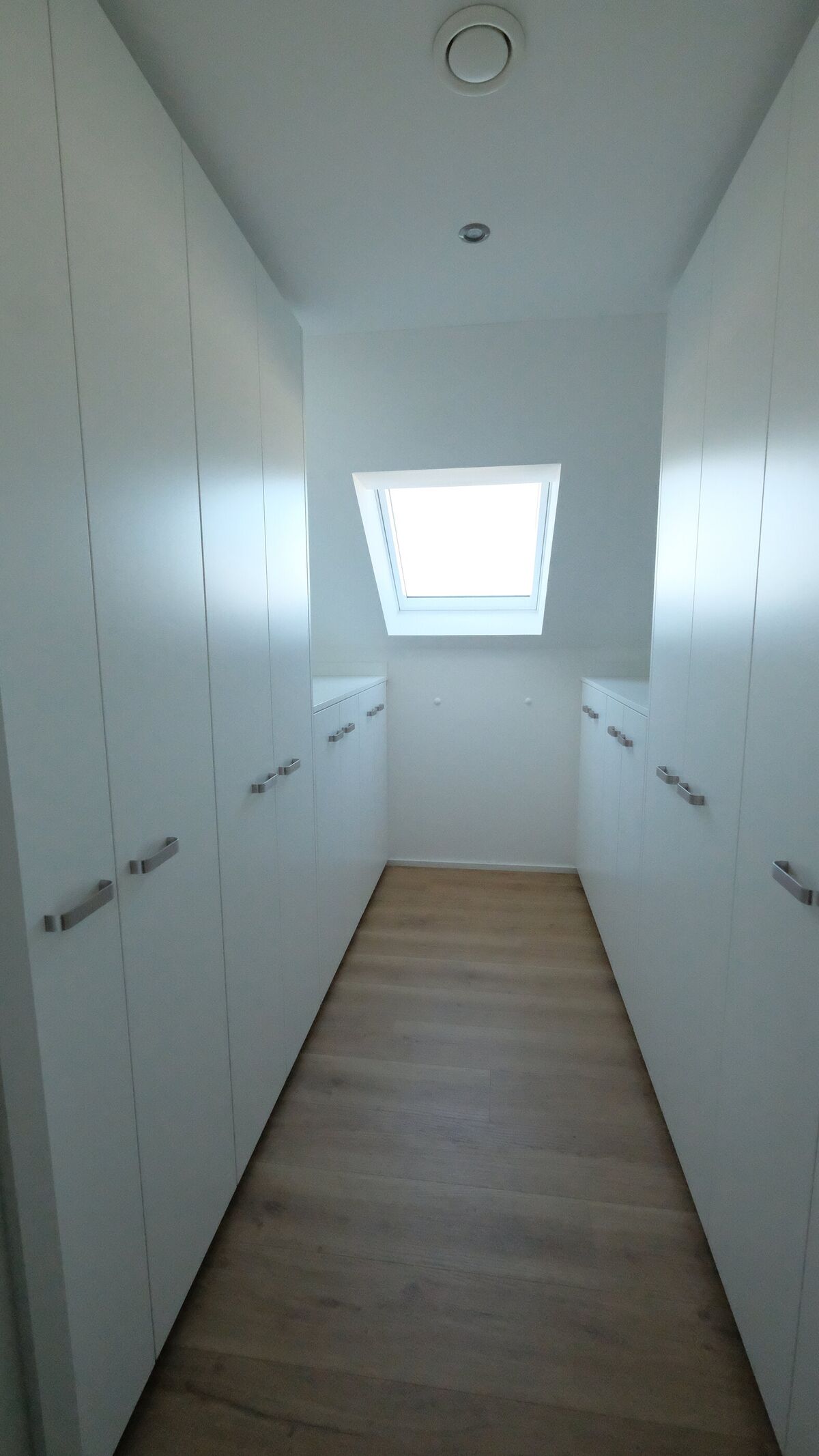 Einbauschrank unter der Dachschräge mit heller Holzwand und Dachfenster