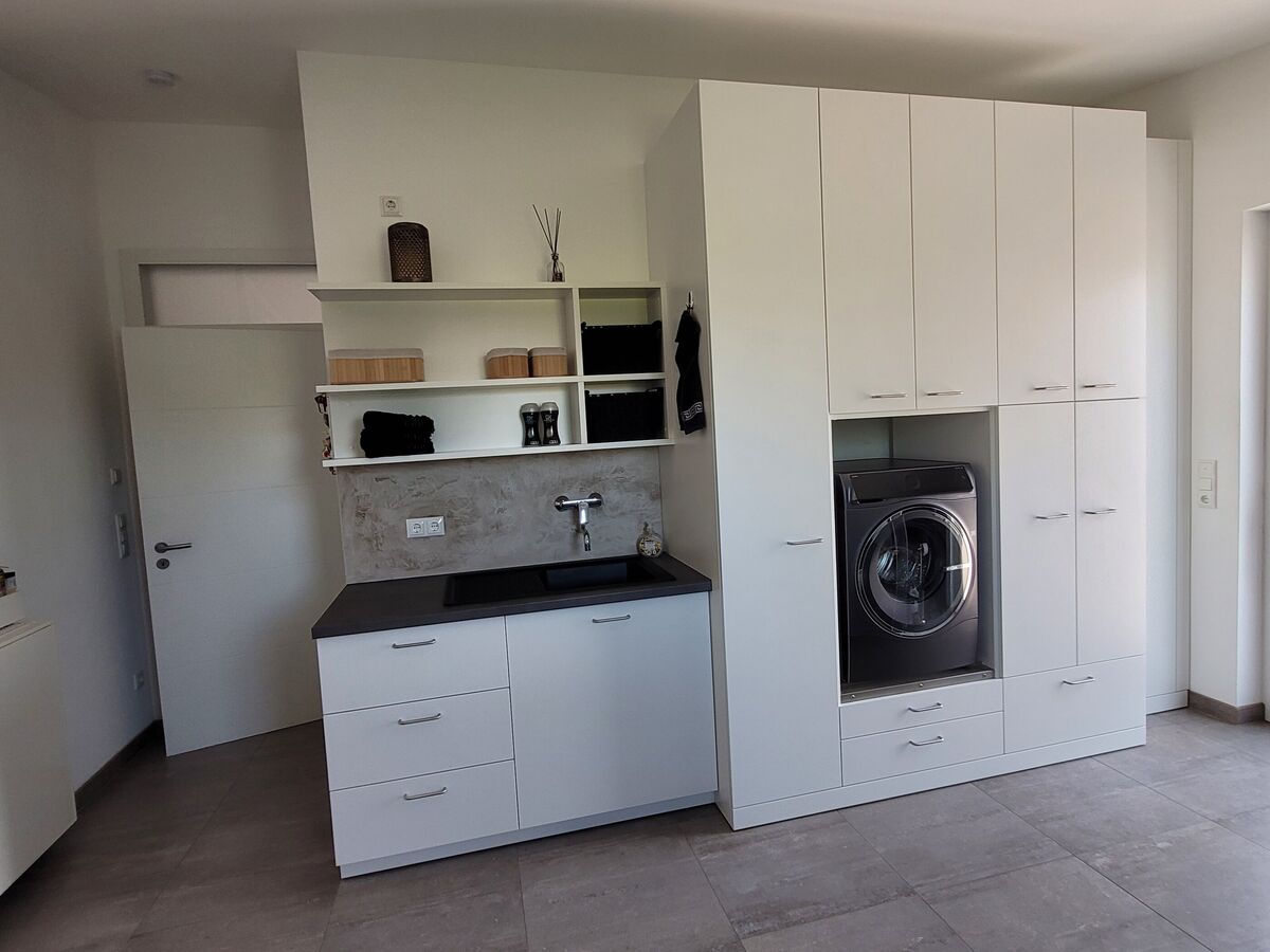 Hauswirtschaftsraum mit Waschmaschine und deckenhohem Stauraum