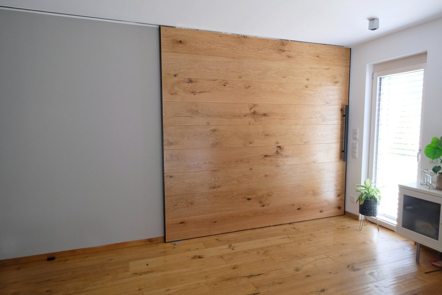 Große Schiebetür aus Altholz mit sichtbarer Struktur vor heller Wand