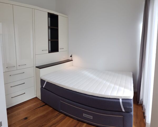Doppelbett mit dunkler Polsterrückwand und beleuchteter Wandnische