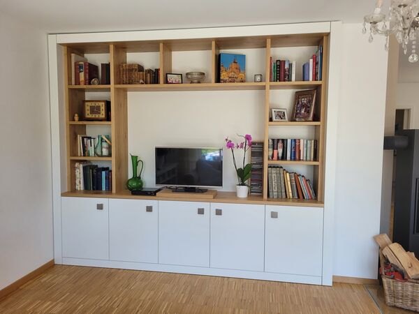 Wohnwand aus Eiche mit offenen Regalfächern, Fernseher und weißen Unterschränken