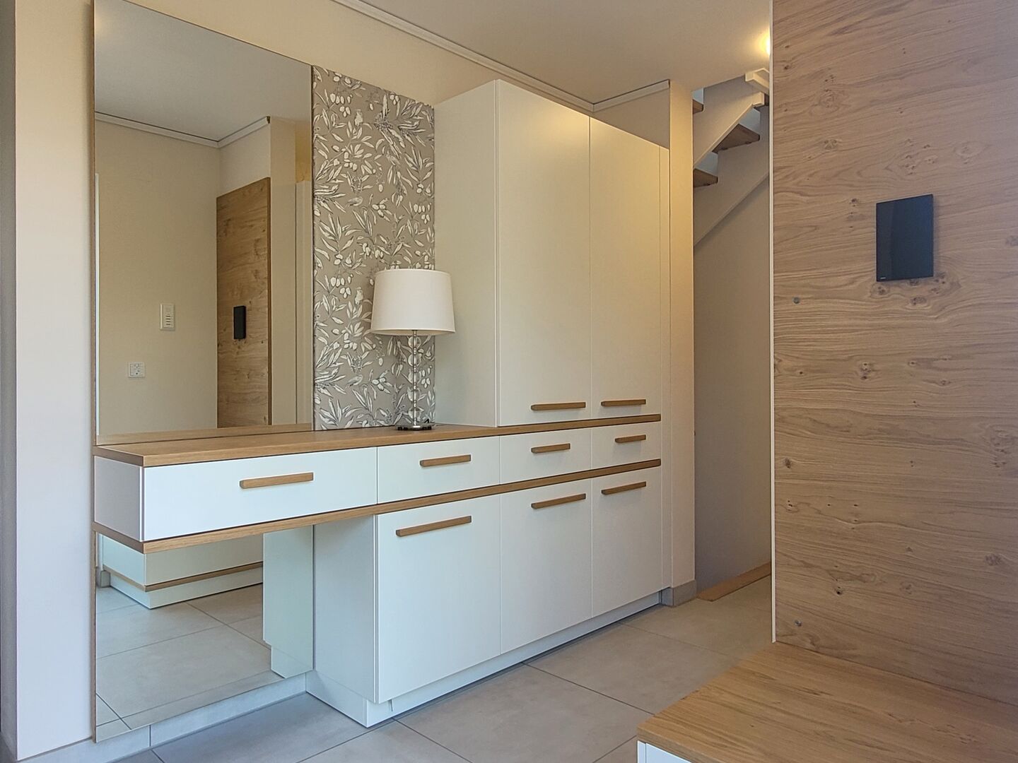 Garderobe mit Sideboard, Spiegel und Holzpaneel im hellen Eingangsbereich