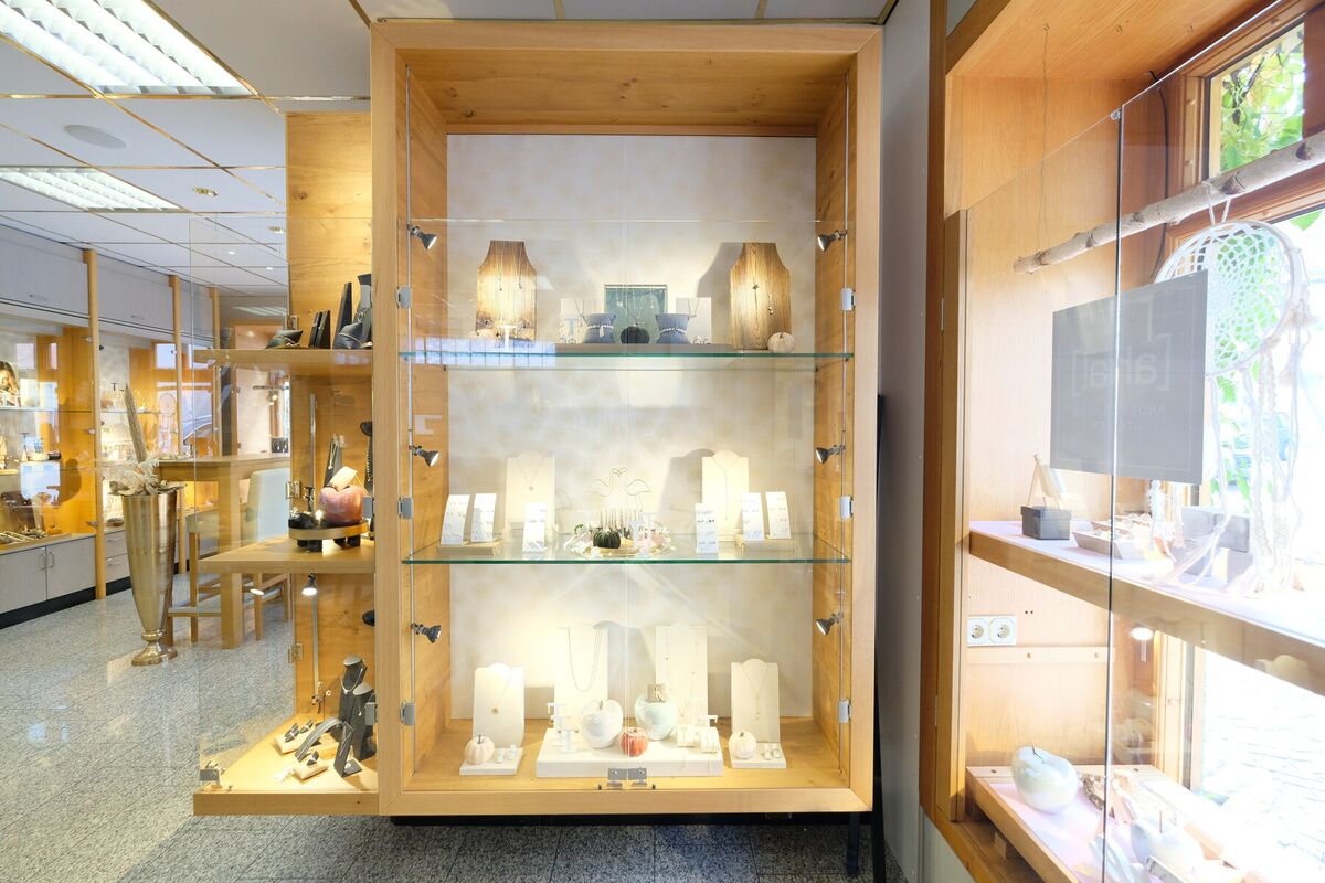 Beleuchtete Vitrine aus Holz mit Glasböden und ausgestellter Ware