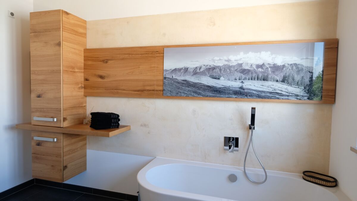 Badewanne vor einer Wandverkleidung aus hellem Holz